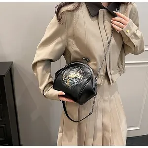 Detail of a vintage black leather shell bag with embroidery and metal chain strap