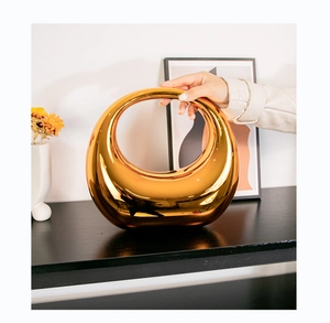 Detail of luxury gold electroplated ceramic moon ring vase with mirror finish on black wood