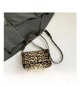 Close-up of retro leopard print flap bag with smooth leather strap on grey blazer