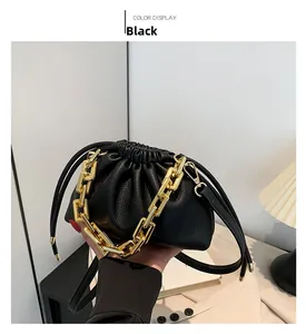 Detail of black dumpling bag with chunky gold chain and lychee textured leather finish
