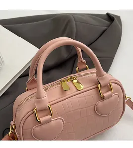 Detail of pink faux crocodile handbag featuring heart-shaped handle bases and gold hardware