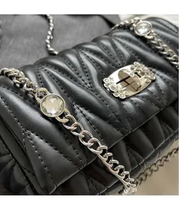Detail of black quilted leather bag featuring V-shaped stitching and crystal-embellished silver lock