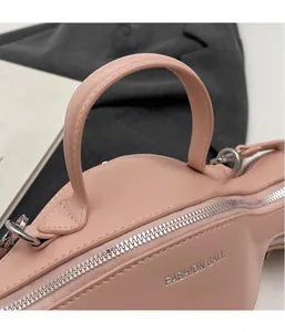 Gros plan du sac à main rose en cuir avec fermeture éclair et logo argenté