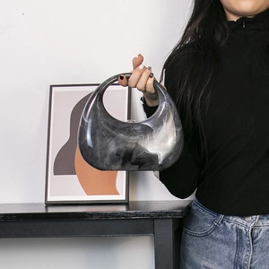 Modern marble pattern acrylic crescent handbag with marble texture held by a model