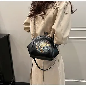 Detail of a vintage black chain crossbody bag with a colorful embossed elephant emblem