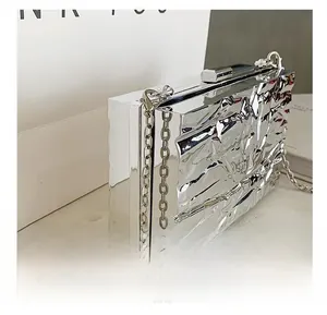 Detail view of the silver metallic quilted texture and iron chain strap on the evening bag