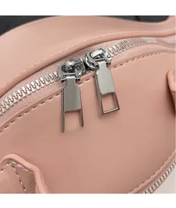 Détail du sac en cuir rose montrant deux fermetures éclair en argent et ferrures polies