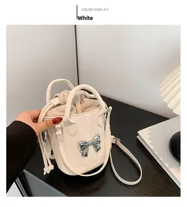 Detail of white bucket bag featuring a silver metal bow and drawstring lining