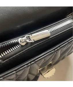 Close-up of silver metal zipper and quilted leather texture on a black crossbody bag