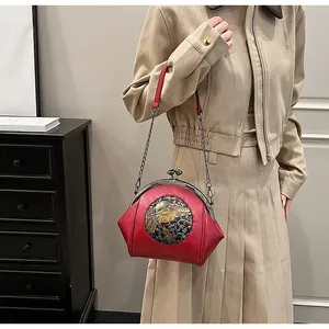 Detail of red vintage shell bag featuring silver elephant relief and metal clasp closure