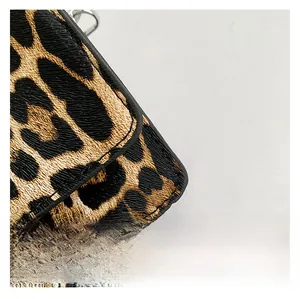Detail of leopard print leather handbag showing stitching and metal buckle components