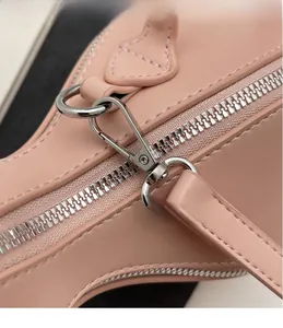 Détail d'un sac à main en cuir rose montrant la fermeture éclair et le crochet en métal