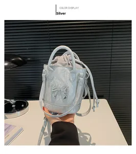 Detail of silver metallic bucket bag with a bow buckle and grey drawstring inner pouch