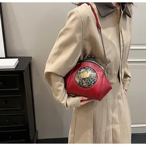 Detailed view of a vintage red shell bag with embroidery and dark metal chain strap