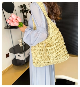 Close-up of hollow woven straw tote bag with elegant pearl tassel charm detail