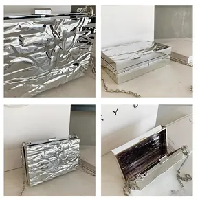 Macro shot of silver textured clutch bag with metal chain and metallic fold detail