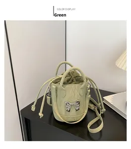 Close-up of green leather bucket bag featuring a silver metal bow and drawstring inner bag