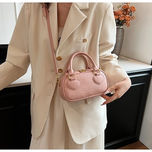 Detail of pink croc-embossed handbag showing heart-shaped patches and gold hardware
