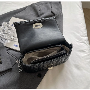 Detailed view of the black quilted shoulder bag interior with chain strap and silver lock