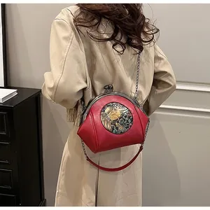 Detail of red vintage shell bag with retro embroidery and silver chain strap on model