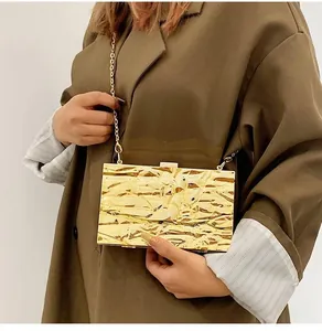Detailed view of golden metallic clutch bag with lava texture and gold chain strap