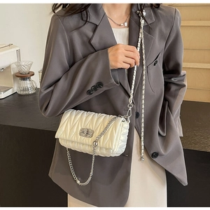 Close-up of white matelassé leather handbag featuring silver chain and metal turn-lock
