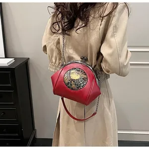 Detail of red vintage shell bag featuring retro elephant embroidery and metal chain strap