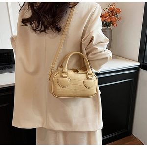 Detail of beige faux crocodile leather handbag with heart applique and gold hardware