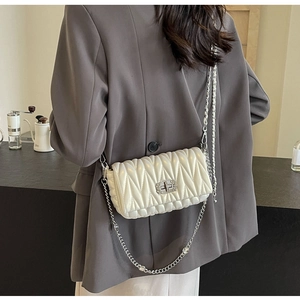 Close-up of quilted off-white crossbody bag with rhinestone chain and metallic lock