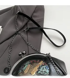 Detail of embroidered elephant pattern on black leather bag with metal chain strap