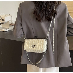Detail shot of white quilted chain bag with crystal buckle on model in chic cafe setting