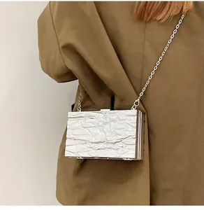 Detail of white pleated texture crossbody evening bag with slim silver chain strap