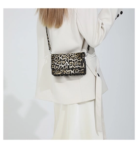 Close-up of leopard print crossbody bag with silver metallic buckles on model outfit