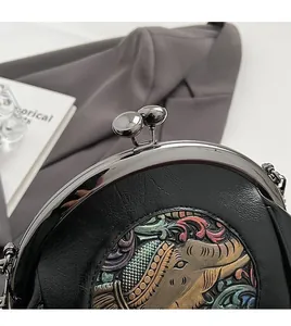 Macro shot of vintage black leather shell bag with colorful embroidery and metal clasp