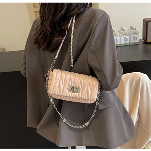 Detail of a quilted crossbody bag with silver crystal chain shown on model back