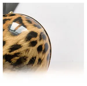 Detail of round leopard print evening bag with glossy finish and gold metal frame