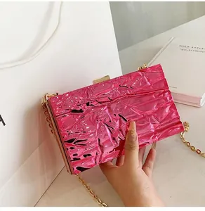 Detailed shot of pink metallic textured clutch bag featuring a gold chain and rectangle handle