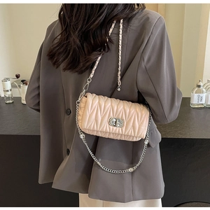 Detail of light pink quilted crossbody bag with rhinestone buckle and silver chain