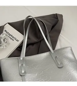 Detailed view of silver tote bag with crinkled metallic texture and reinforced shoulder straps