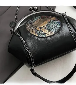 Detail of black shell bag featuring embroidery and vintage elephant metal clasp closure