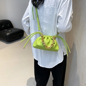 Vibrant green bucket bag with lychee texture and chunky gold chain strap on model