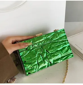 Detail of green metallic pleated box clutch with gold chain strap for evening wear
