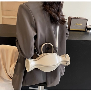 Détail d'un sac à bandoulière crème en forme de bonbon avec sangle réglable et zip métallique