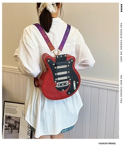 Détail d'un sac à dos en forme de guitare rouge et noir avec des sangles à notes de musique
