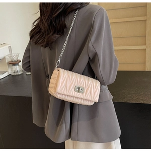 Detail of light pink quilted leather bag with silver chain strap and metal swivel lock