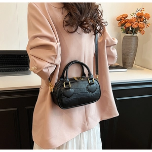 Detail of black crocodile texture handbag with heart-shaped handle base accents and gold hardware
