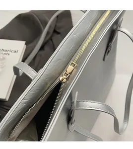 Detailed macro view of the gold zipper and silver textured faux leather on a tote bag