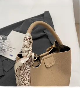 Détail d'un sac seau en cuir marron avec un foulard en soie chic décorant la poignée