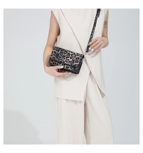 Close-up of a stylish leopard print crossbody bag worn by a model in a minimalist studio