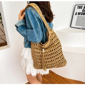 Detail of straw tote bag with hollow weave, decorative tassels and pearl accents